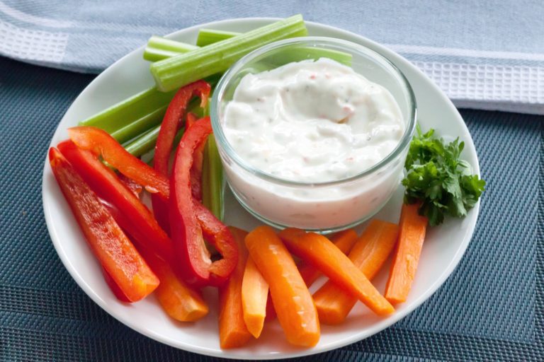Sliced vegetables and dip on a white platter perfect healthy snack food